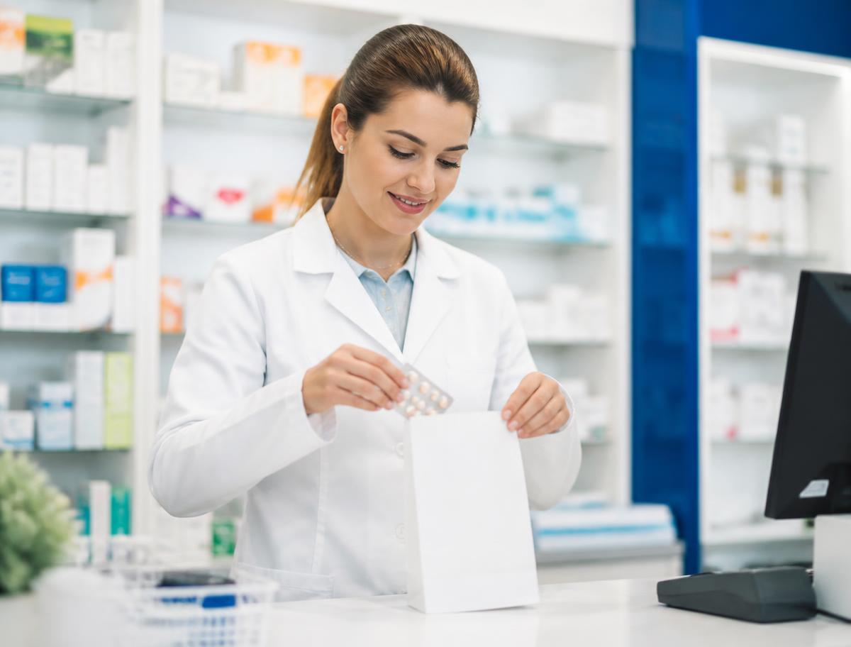 Pharmacist packaging medication into a prescription bag